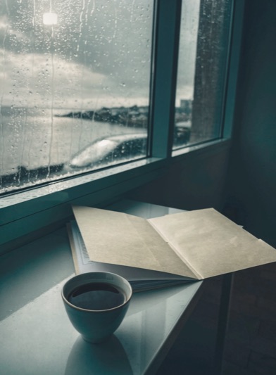 An insurance file open on a desk beside a rain-streaked window