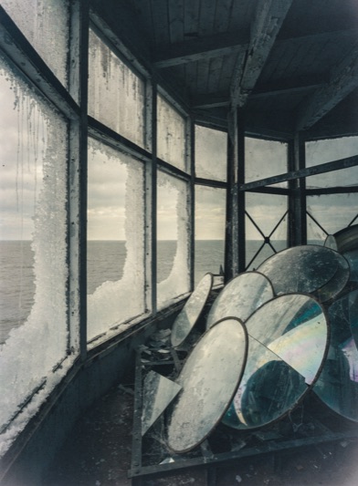 A darkened lighthouse seen from the shore